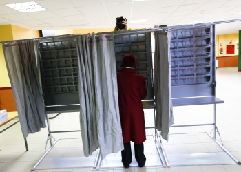 A camera appears over a vooting booth as a woman prepares her ballot before voting in Spain's general election in Madrid, Spain, December 20, 2015.  REUTERS/Marcelo Del Pozo  - RTX1ZG9S