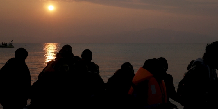 Refugees are silhouetted as they reach the shores of the Greek island of Lesbos on a dinghy during sunrise, March 20, 2016. REUTERS/Alkis Konstantinidis - RTSBA5L
