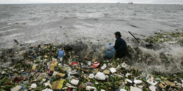 A man collects recyclable plastic materials, washed ashore by waves, which will be sold for 21 pesos ($0.48) in exchange for food in Manila  August 2, 2008. REUTERS/Cheryl Ravelo (PHILIPPINES) - RTR20K6N