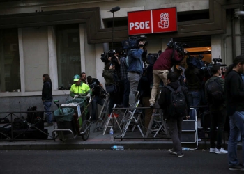 A municipal cleaner works next to the media as they stand outside the headquarters of Spain's Socialist party (PSOE) while waiting for the start of the party's assembly meeting in Madrid, Spain, October 1, 2016. REUTERS/Susana Vera - RTSQB55