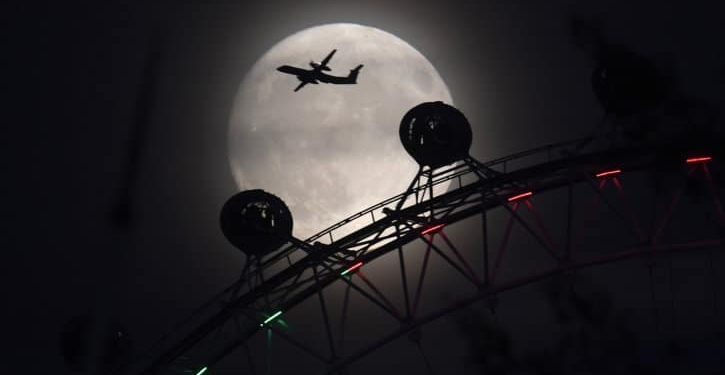 Un avión vuela más allá de la rueda del ojo de Londres, y la luna, un día antes del espectáculo "súper luna" en Londres, Gran Bretaña. REUTERS /