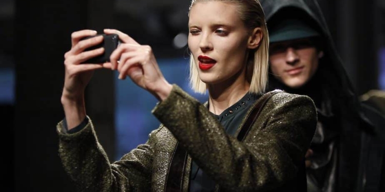 A model takes a photo with a smart phone as she presents a creation from the Kenneth Cole Autumn/Winter 2013 collection during New York Fashion Week in New York, February 7, 2013. REUTERS/Carlo Allegri  (UNITED STATES - Tags: FASHION) - RTR3DHHH