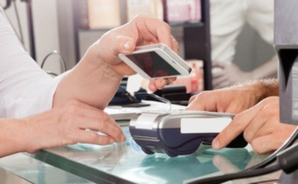 Female customer paying with mobilephone using NFC in hair salon