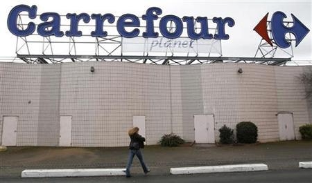 A woman walks below the logo of Carrefour Planet supermarket in Bordeaux, southwestern France, January 19, 2012. REUTERS/Regis Duvignau
