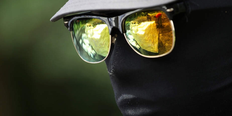 Un soldado está de guardia cuando los trabajadores que mueven paquetes que contienen cocaína y otras sustancias para la incineración se reflejan en sus gafas de sol, en una base militar en Santo Domingo