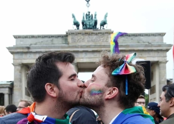 Una pareja se ve besándose mientras la gente celebra el parlamento de Alemania que legaliza el matrimonio entre personas del mismo sexo frente a la Puerta de Brandenburgo en Berlín, Alemania