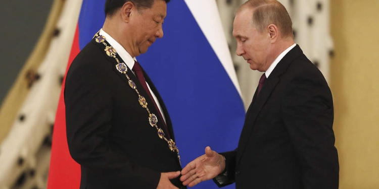 El presidente ruso Vladimir Putin (R) estrecha la mano con su homólogo chino Xi Jinping después de concederle la Orden de San Andrés Apóstol el Primero Calificado durante una reunión