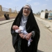 Una anciana iraquí desplazada que huyó de militantes islámicos lleva a un bebé en Mosul, Irak