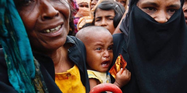 Un bebé refugiado rohingya llora mientras su madre se apresura a pedir ayuda en Cox's Bazar, Bangladesh