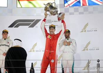 Formula 1 F1 - Bahrain Grand Prix - Bahrain International Circuit, Sakhir, Bahrain - April 8, 2018   Ferrari's Sebastian Vettel celebrates with the trophy after winning the race as Mercedes' Valtteri Bottas and Mercedes' Lewis Hamilton look on   REUTERS/Hamad I Mohammed