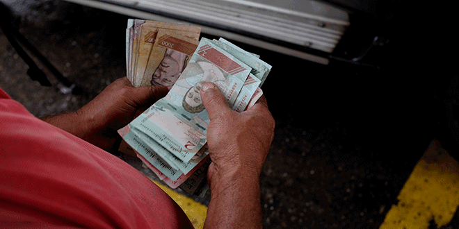 Un trabajador de una gasolinera de PDVSA cuenta bolívares en Caracas, sep 24, 2018. REUTERS/Marco Bello
