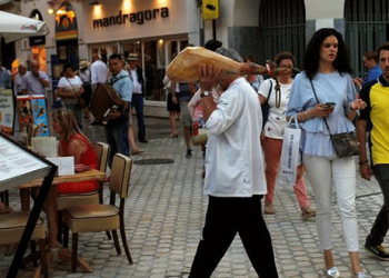 Un camarero lleva un jamón en una terraza de un resturante en el centro de Málaga, el 7 de junio de 2018. REUTERS/Jon Nazca