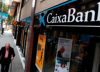 En la imagen de archivo, un hombre camina junto a una sucursal de Caixabank en Barcelona, España. REUTERS/Yves Herman