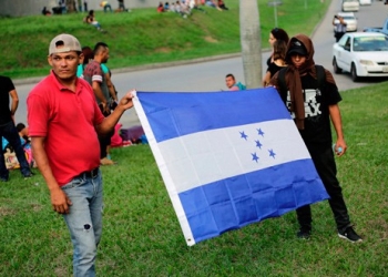 Personas sostienen una bandera de Honduras mientras esperan salir con una nueva caravana de migrantes, que se dirigirá a Estados Unidos, en una estación de autobuses en San Pedro Sula, Honduras, 14 de enero del 2019. REUTERS/Jorge Cabrera