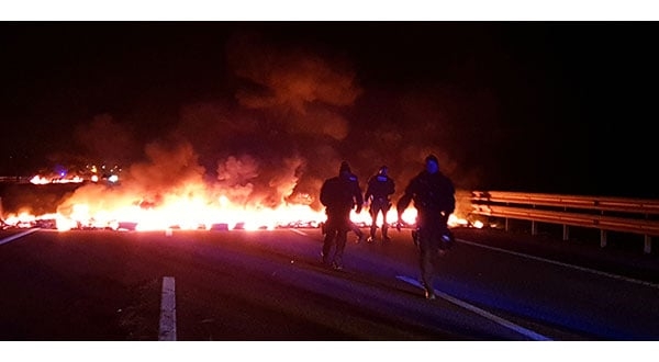 Agentes de policía junto a barricadas en llamas que intentaron bloquear la autopista AP7 durante una huelga general cerca de Girona.