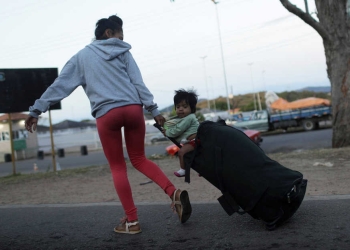 A woman pulls a suitcase with a child sitting on top, after crossing the border from Venezuela to Brazil in Pacaraima, Roraima state, Brazil, February 22, 2019. REUTERS/Ricardo Moraes