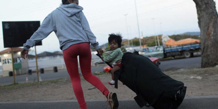 A woman pulls a suitcase with a child sitting on top, after crossing the border from Venezuela to Brazil in Pacaraima, Roraima state, Brazil, February 22, 2019. REUTERS/Ricardo Moraes