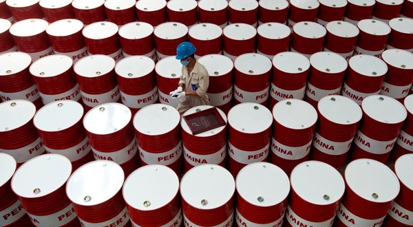Un trabajador etiqueta barriles de lubricante de petróleo.