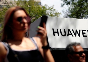 Transeúntes caminando frente a un logo de Huawei en Ciudad de México.