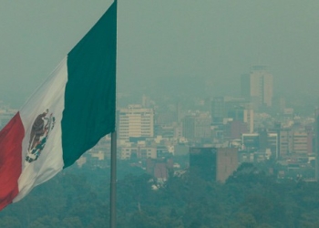 Una vista general muestra la bandera de México enfrente de unos edificios cubiertos por la contaminación atmosférica en Ciudad de México.