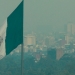 Una vista general muestra la bandera de México enfrente de unos edificios cubiertos por la contaminación atmosférica en Ciudad de México.