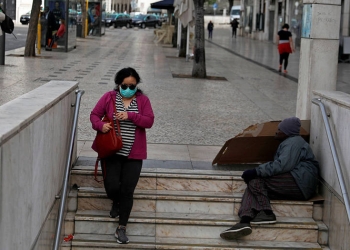 En la esquina de Rossio, en Lisboa, una mujer con mascarilla para evitar la propagación del COVID-19 entra a la estación del metro, el 19 de marzo