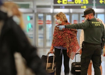 Un oficial de la guardia civil con una máscara protectora hace gestos mientras habla con los pasajeros en el aeropuerto Josep Tarradellas de Barcelona-El Prat, luego de que el gobierno español anunciara que a partir del 15 de mayo todas las personas que ingresen a España tendrán que permanecer en cuarentena durante dos semanas, en medio de la enfermedad por coronavirus. (COVID-19) brote en Barcelona, España 14 de mayo de 2020. REUTERS / Nacho Doce