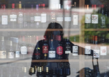 Una mujer se refleja en el escaparate de una tienda mientras espera entrar, durante el brote de la enfermedad por coronavirus (COVID-19), en Ronda, sur de España, el 3 de abril de 2020. REUTERS / Jon Nazca