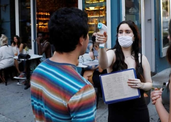 Una camarera toma la temperatura de los clientes cuando llegan a comer, como parte de la reapertura de la fase 2 durante el brote de la enfermedad por coronavirus (COVID-19) en Manhattan, EE. UU. 27 de junio de 2020. REUTERS / Andrew Kelly