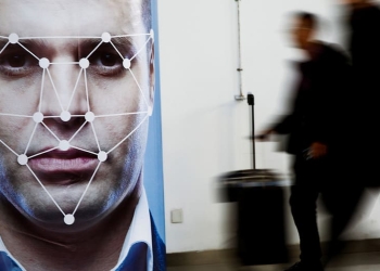 La gente pasa junto a un póster que simula el software de reconocimiento facial en la exposición Security China 2018 sobre seguridad pública en Beijing, China, 24 de octubre de 2018. REUTERS / Thomas Peter