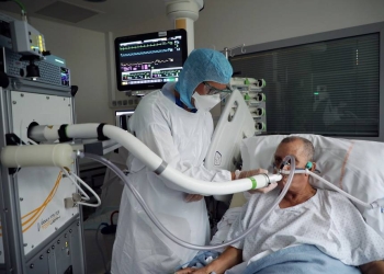 Christian George, Director of Research at the National Centre of Scientific Research, helps a patient suffering from coronavirus disease (COVID-19) to use the COVID-19 'Breathalyzer' test machine  at the La Croix-Rousse Hospital in Lyon, France, July 22, 2020. Picture taken July 22, 2020. REUTERS/Yiming Woo  NO RESALES. NO ARCHIVES