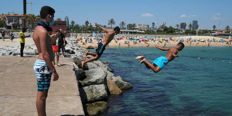 Hombres se lanzan al agua mientras que disfrutan del sol en la playa después de que se anunciaron limitaciones para contener la propagación de la enfermedad por el nuevo coronavirus COVID-19 en Barcelona, España. 19 de julio de 2020. REUTERS/Nacho Doce