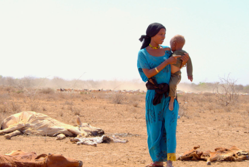 UNICEF/Oloo Una madre con su hijo en brazos caminado junto a los cadáveres del ganado muerto a causa de la grave sequía en Marsabit, en Kenya.